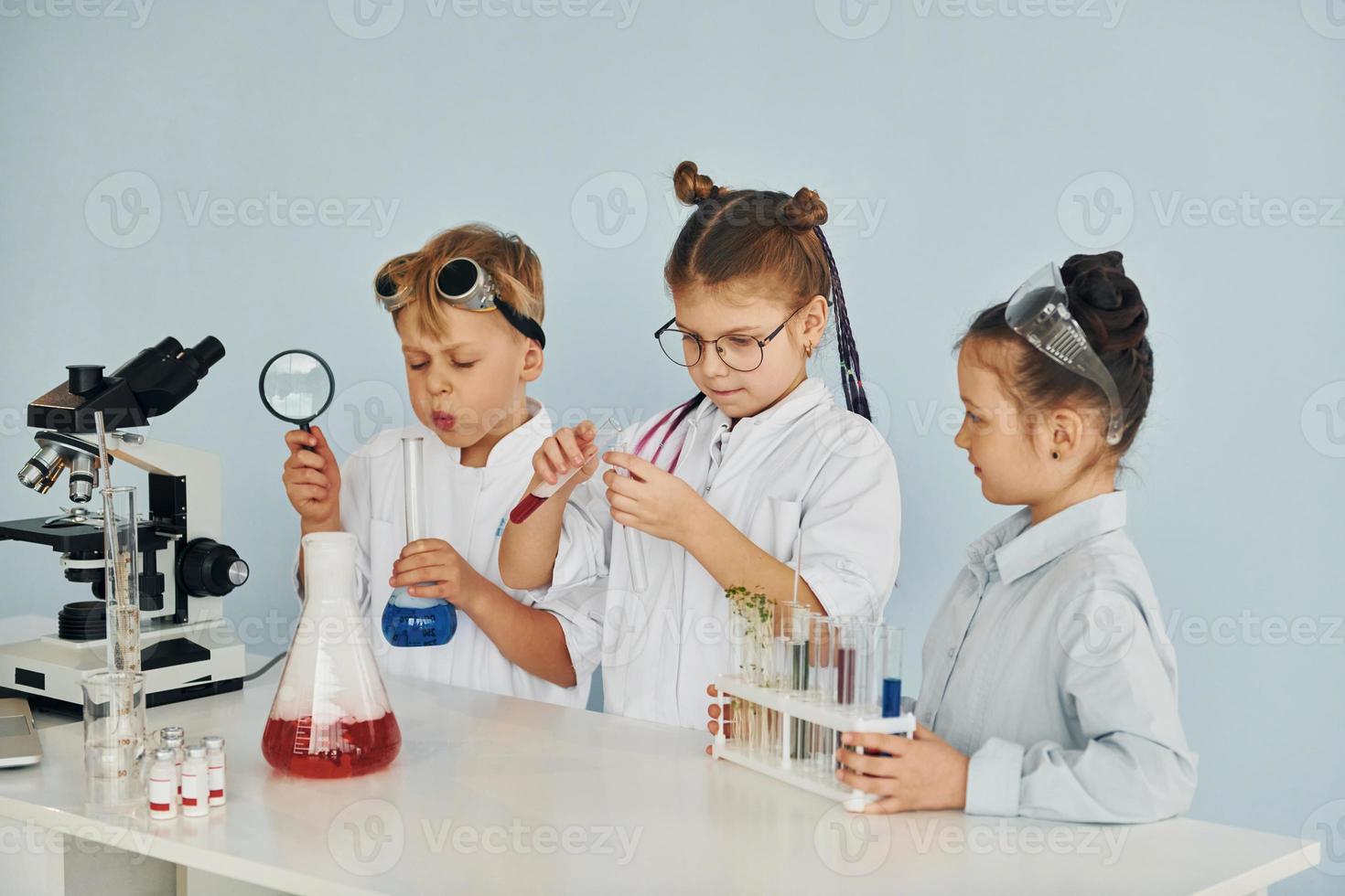 Children in white coats plays a scientists in lab by using equipment photo