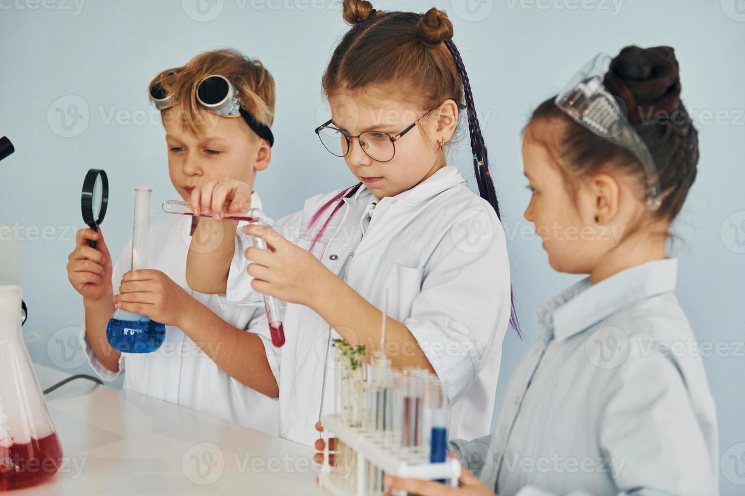Children in white coats plays a scientists in lab by using equipment photo