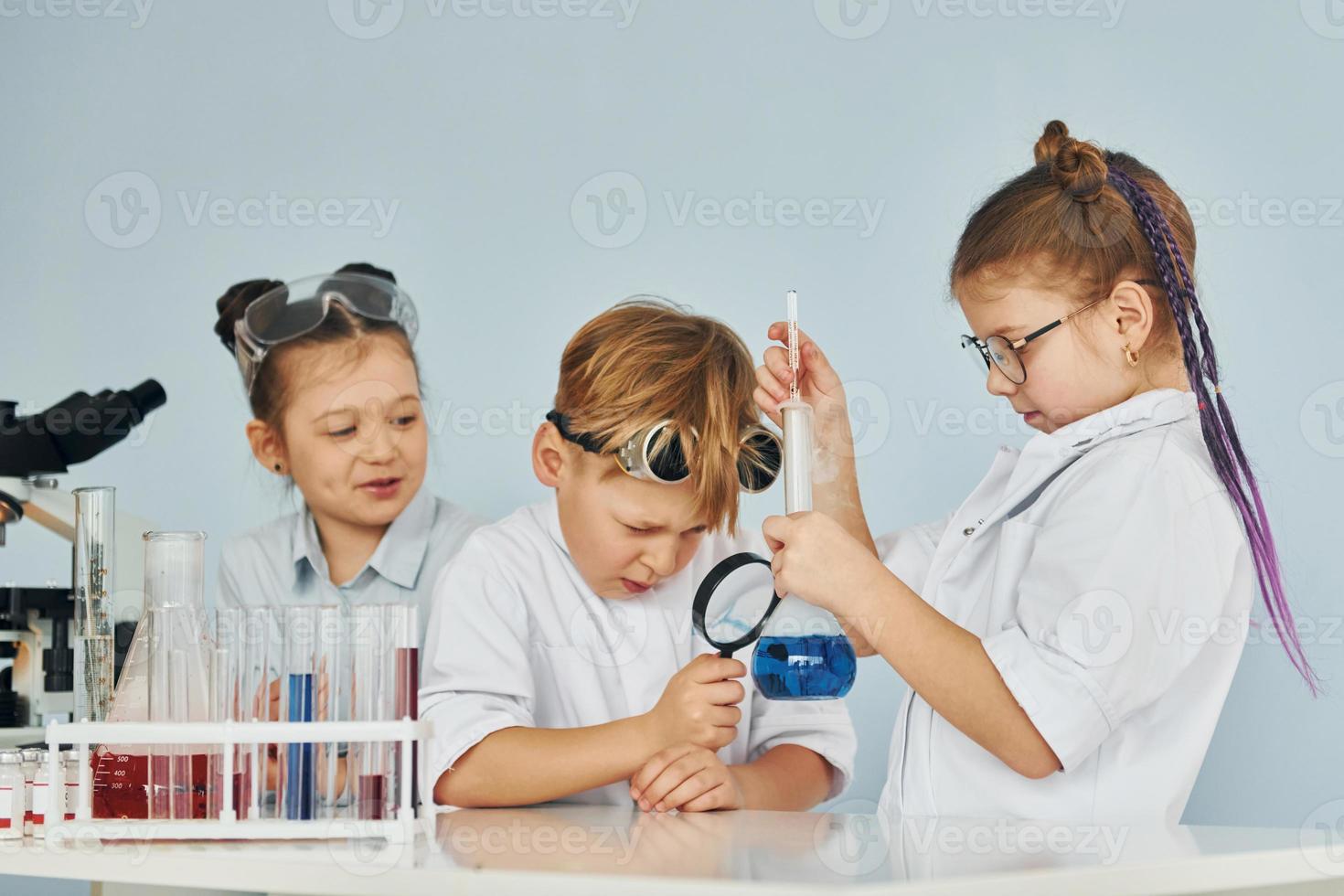 Children in white coats plays a scientists in lab by using equipment photo