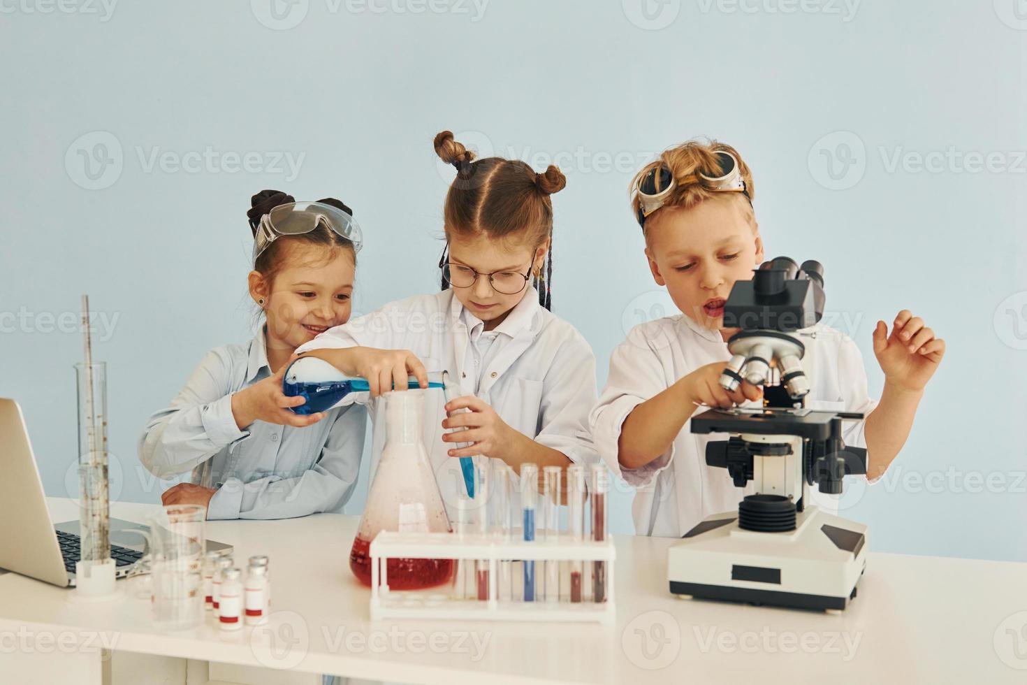 Test tubes with colorful liquid. Children in white coats plays a scientists in lab by using equipment photo