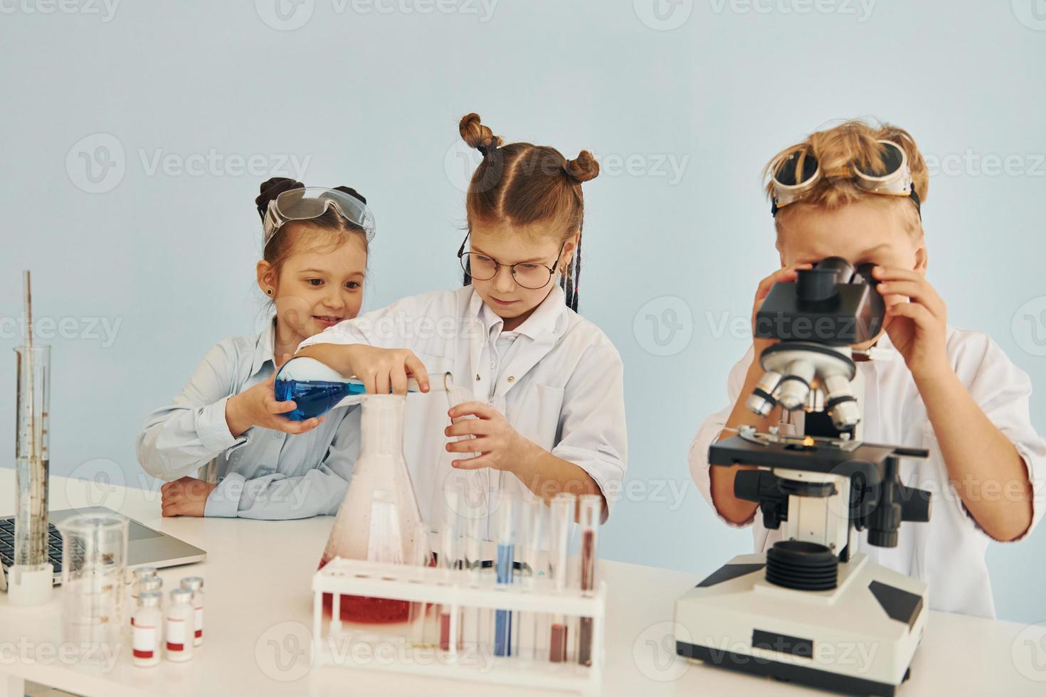 Test tubes with colorful liquid. Children in white coats plays a scientists in lab by using equipment photo