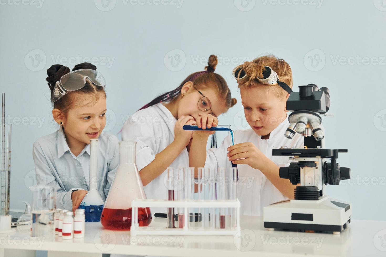 Test tubes with colorful liquid. Children in white coats plays a scientists in lab by using equipment photo