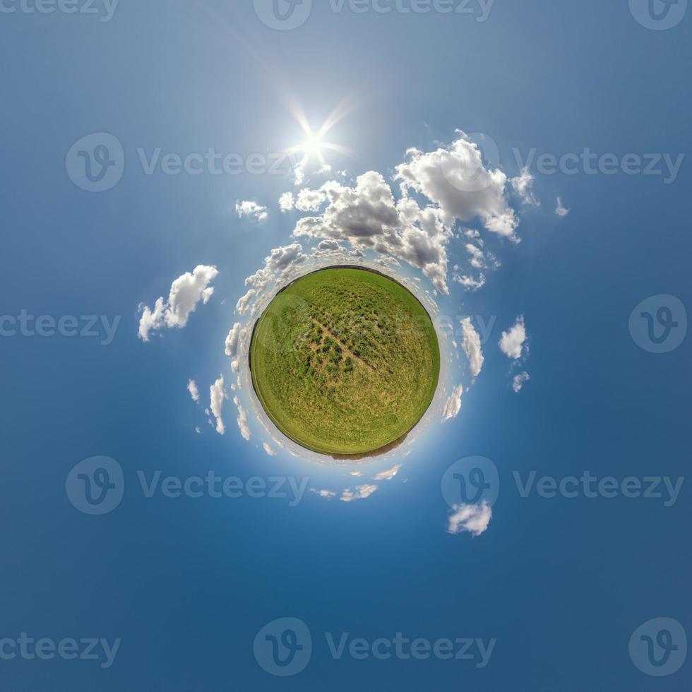 green tiny planet in blue sky with beautiful clouds with transformation of spherical panorama 360 degrees. Curvature of space. photo