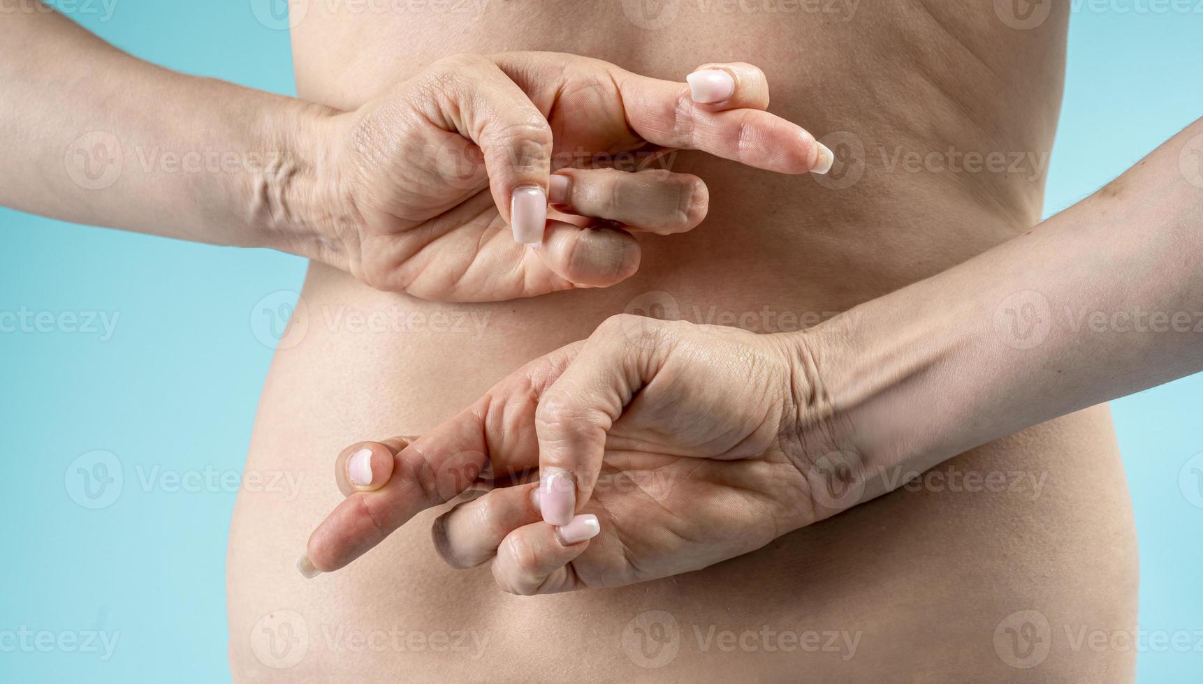 woman hiding a good luck hand sign behind back, isolated on blue background. photo