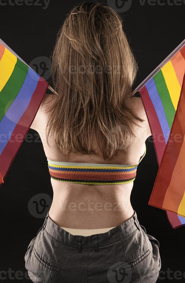 Lesbian woman holding rainbow flag isolated on black background. LGBT International symbol of the lesbian, gay, bisexual and transgender community. photo