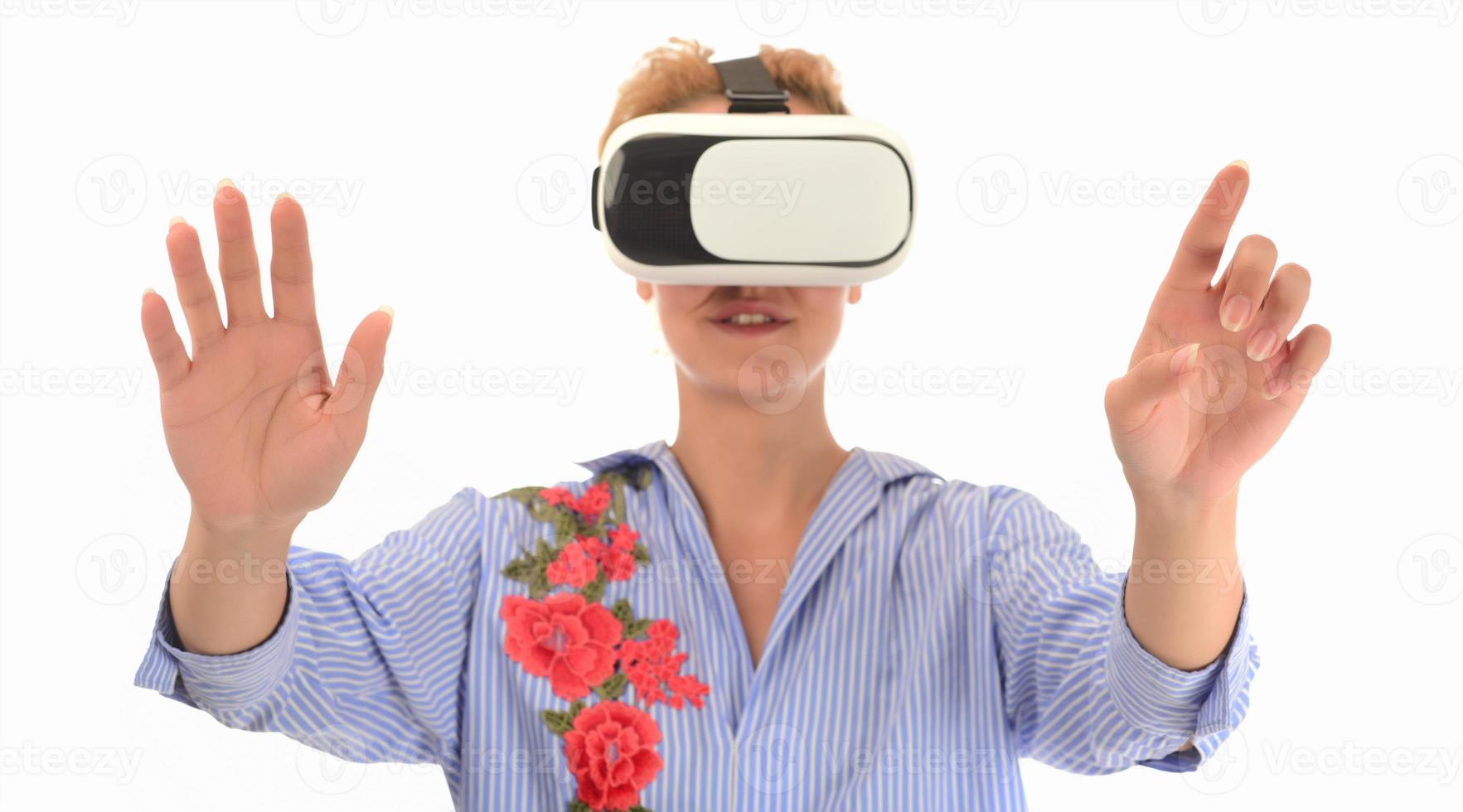 Pretty cute excited female in VR headset looking up and trying to touch objects in virtual reality photo