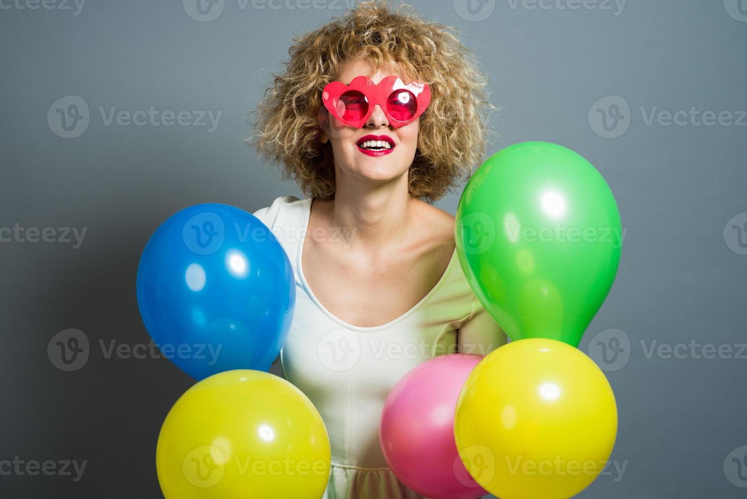 Beautiful Blonde Female Model Holding balloons around her head. Isolated photo