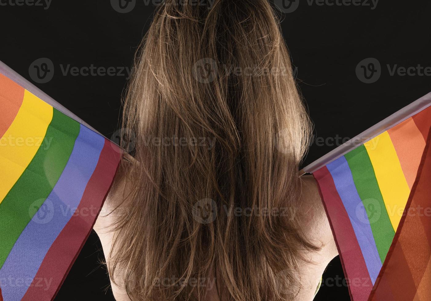 Lesbian woman holding rainbow flag isolated on black background. LGBT International symbol of the lesbian, gay, bisexual and transgender community. photo