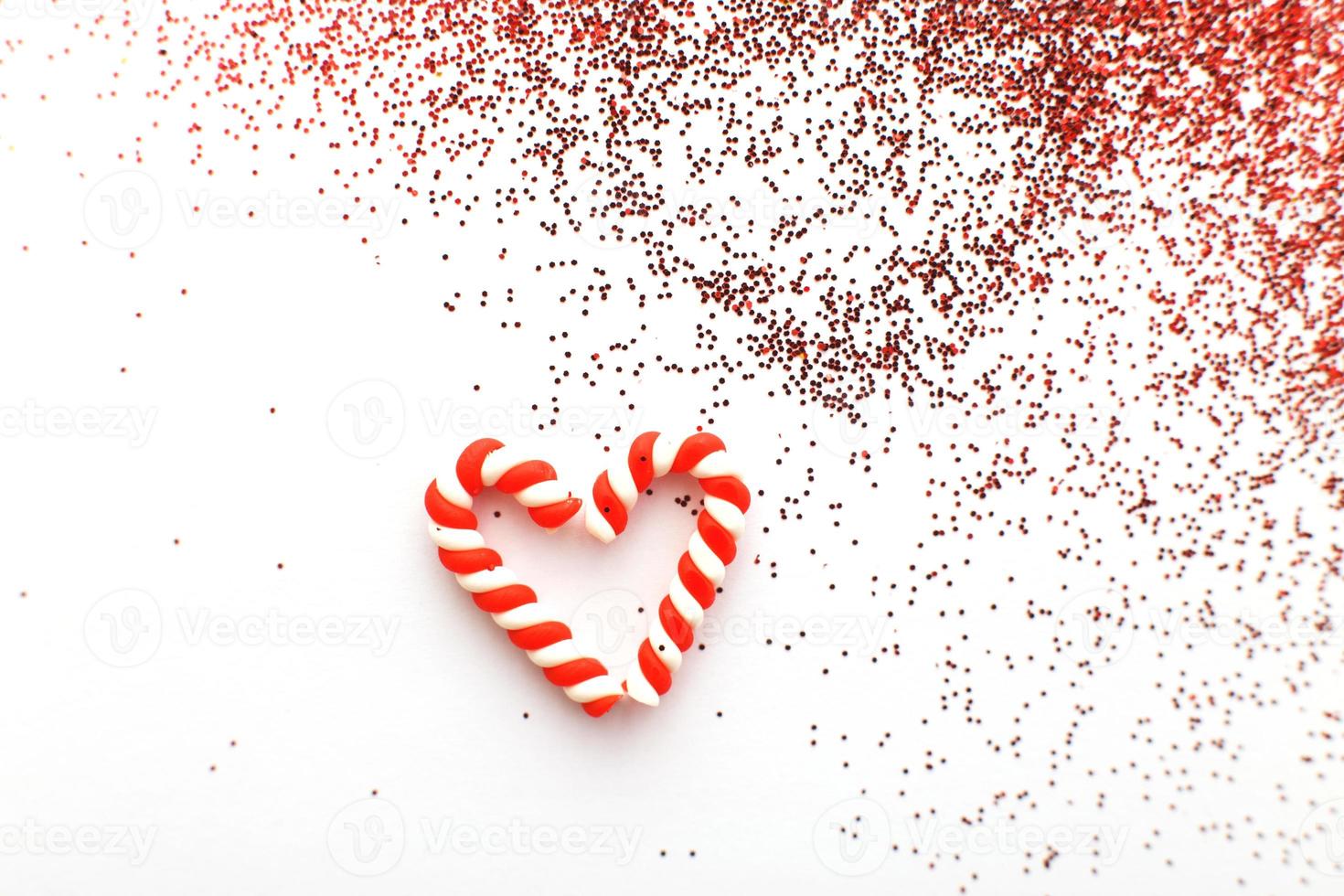 Christmas composition with candy canes in form oh heart on blue wooden background with red sequins photo