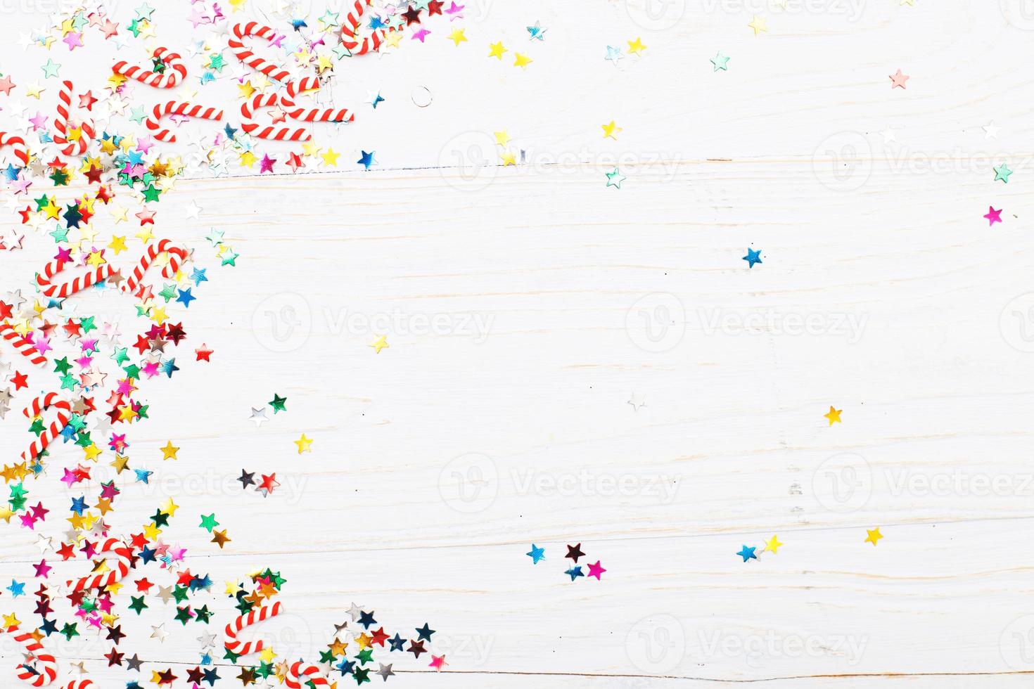 Christmas background with candy canes and multicolored sequins on blue wooden background photo