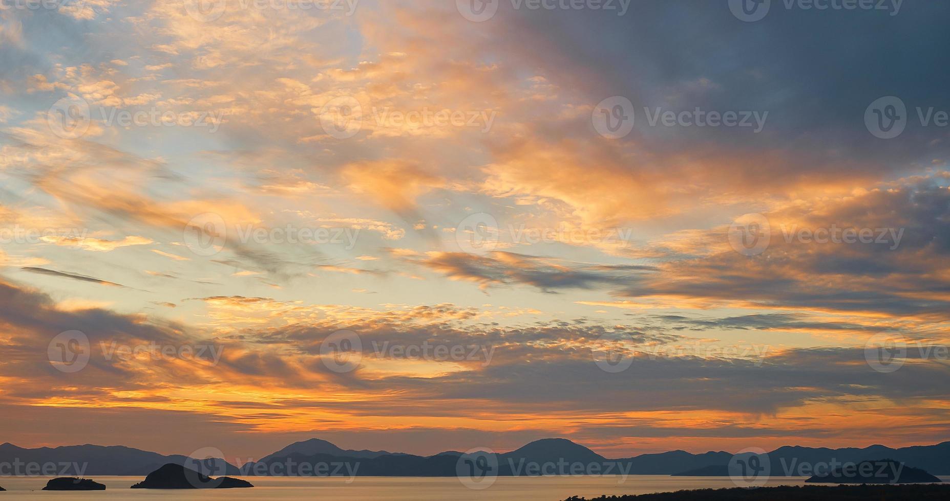 Gorgeous sunset sky with clouds over the sea. Silhouettes of a range of islands and mountains on the horizon. Idea for backgrounds or screens. Dramatic sunset, beauty of nature, vacation time photo