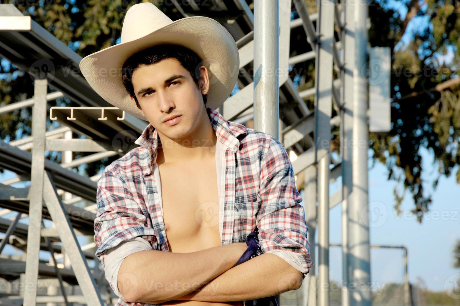 A sexy young cowboy poses with his shirt open to show his masculine and muscular body. photo