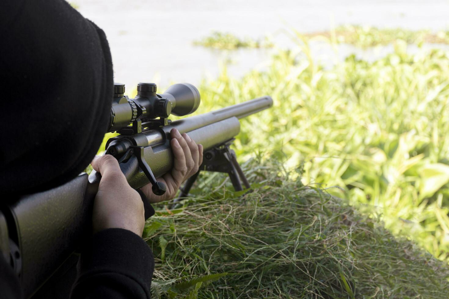 hombre con un rifle mirando a través del alcance foto