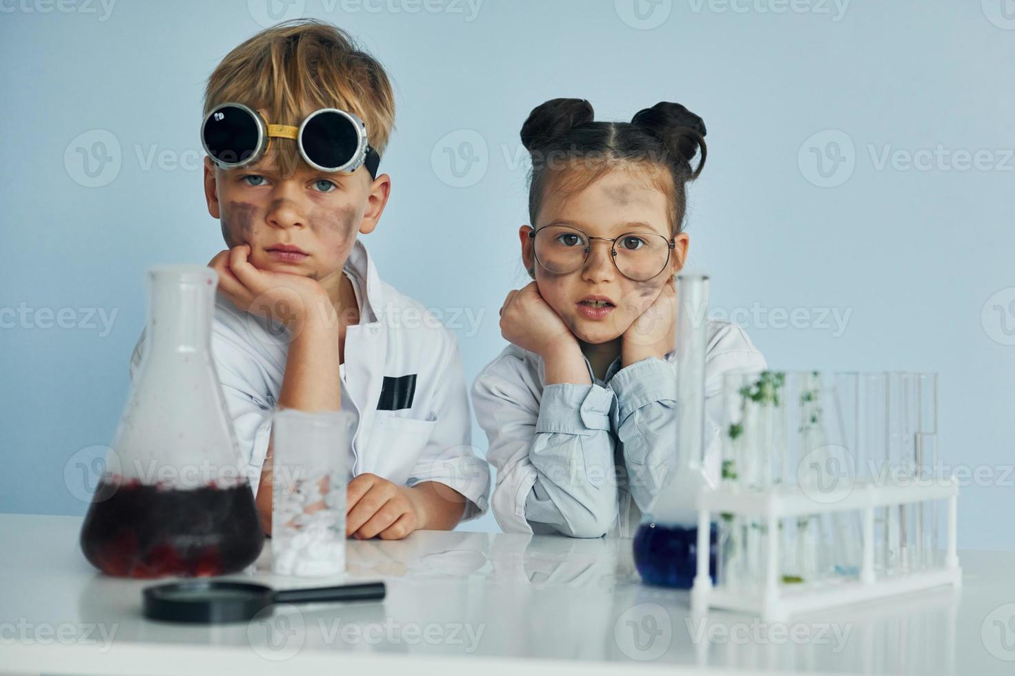 Girl with boy working together. Children in white coats plays a scientists in lab by using equipment photo
