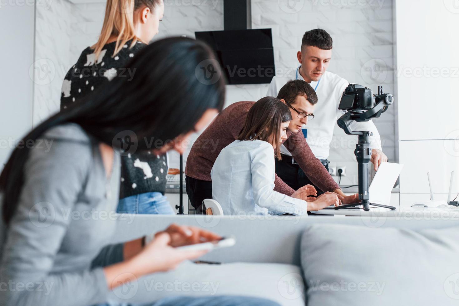 Crew of photographers and models is indoors in the modern room photo