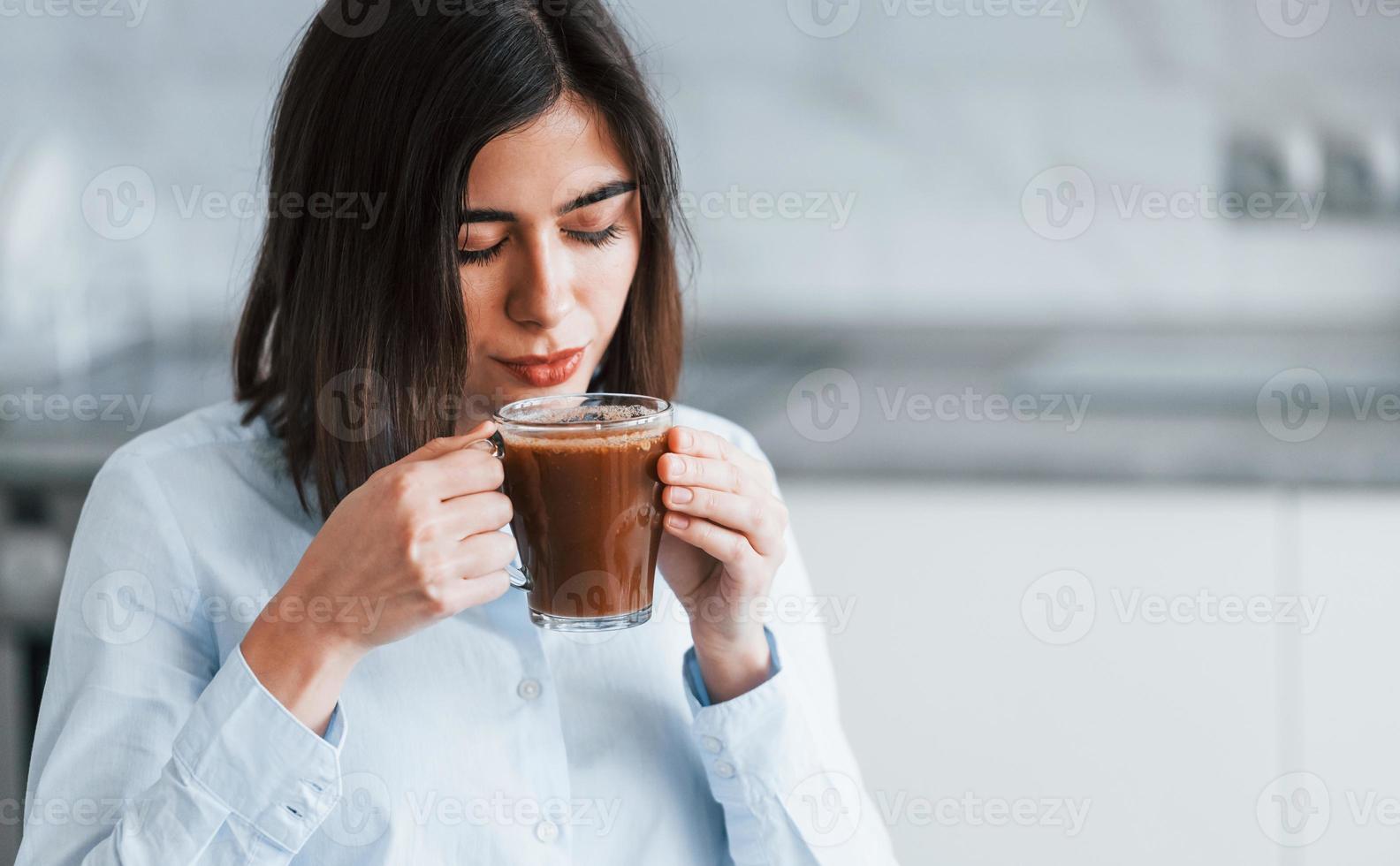 con taza de café. la mujer joven está adentro en la habitación de la casa moderna durante el día foto