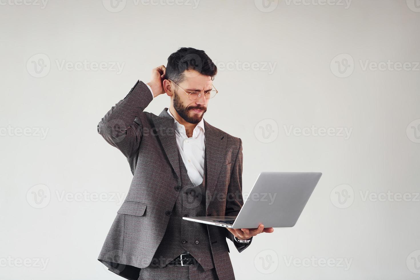 With laptop in hands. Young stylish businessman in suit indoors. Conception of success photo