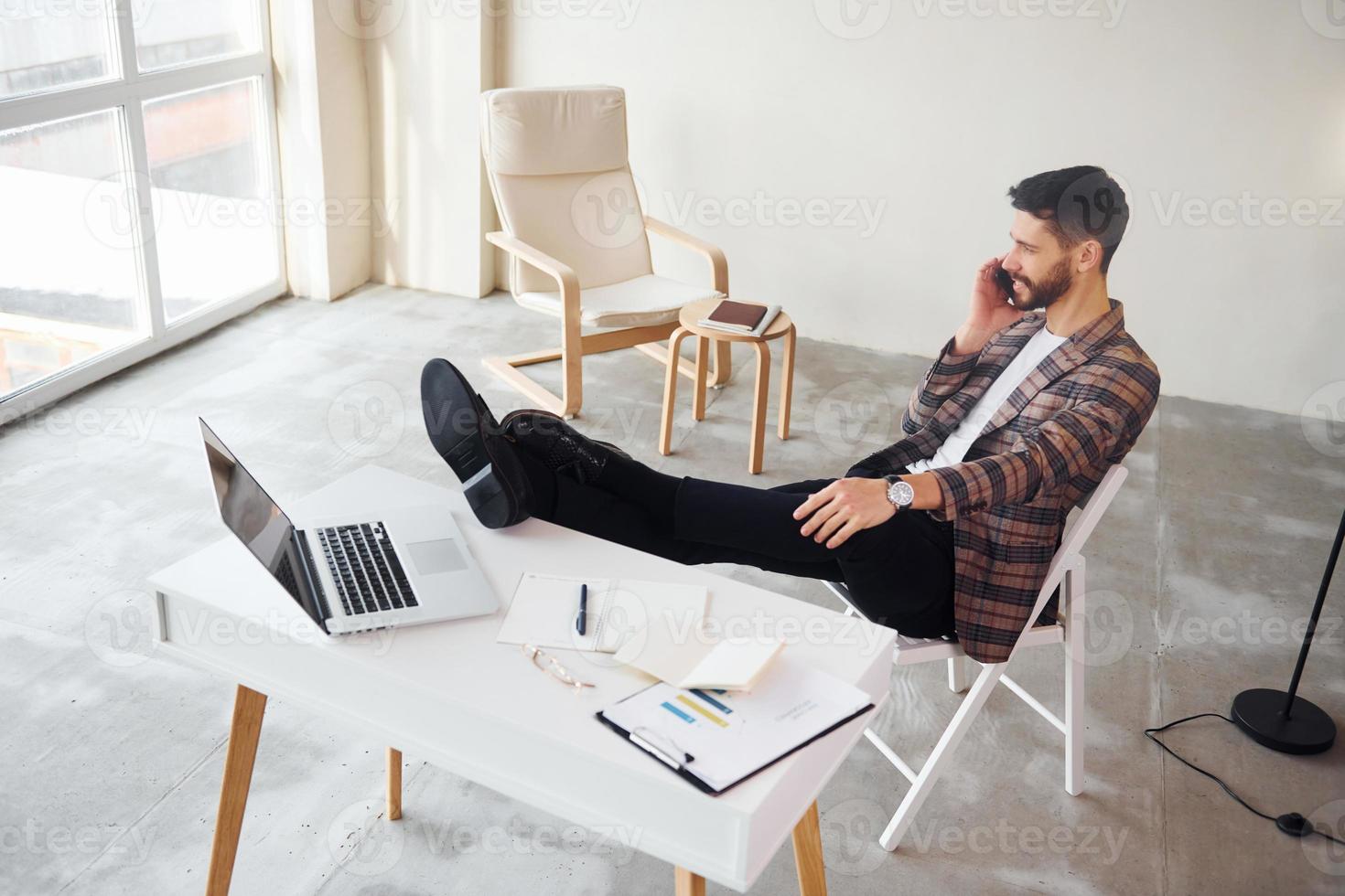 Have conversation by phone. Young stylish businessman in suit indoors. Conception of success photo