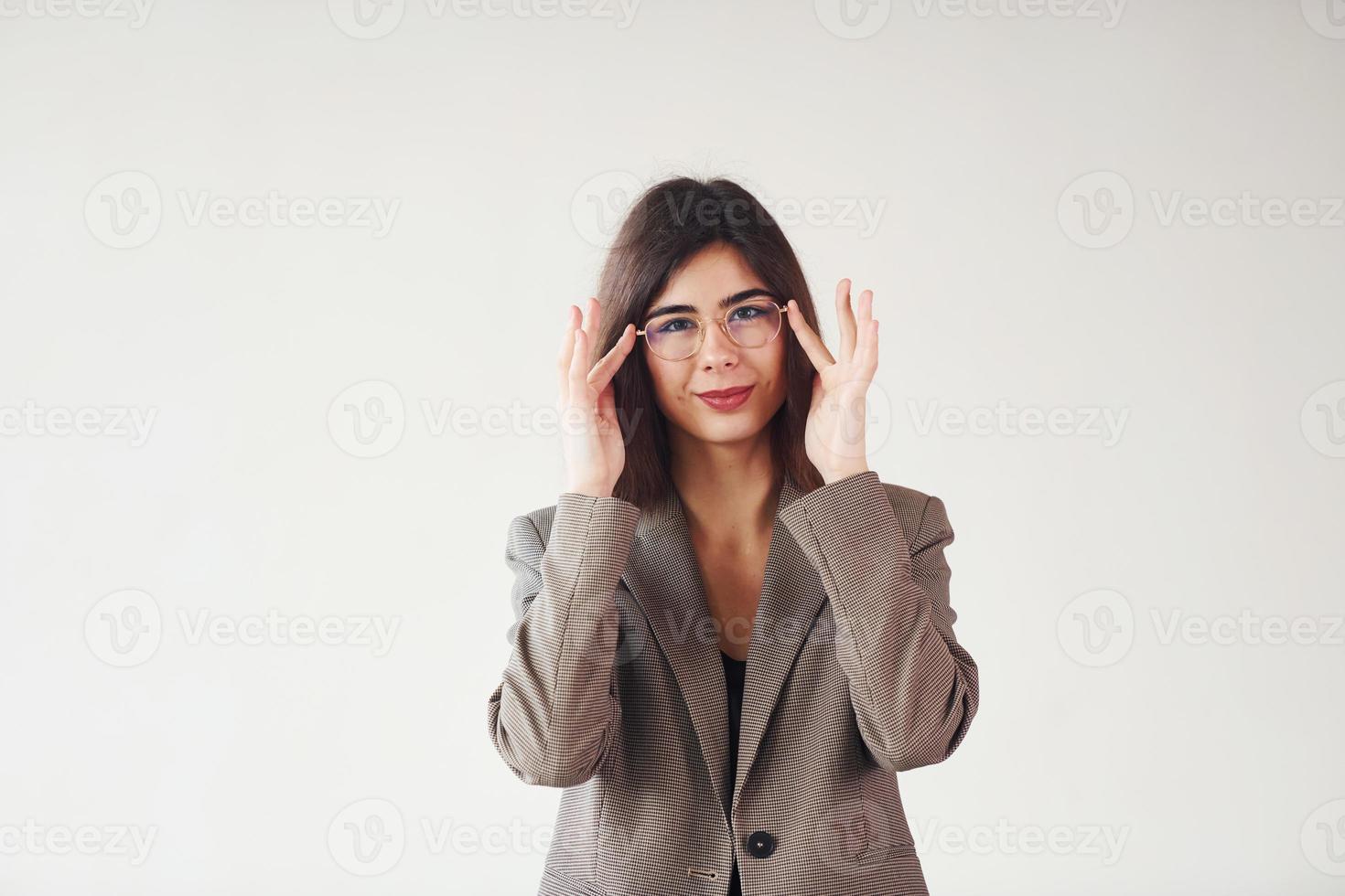 mujer joven en ropa formal está de pie contra el fondo blanco en el estudio foto