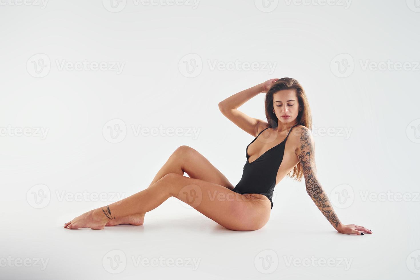 Sits on the ground. Beautiful seductive sporty woman with sexy body is posing in the studio photo