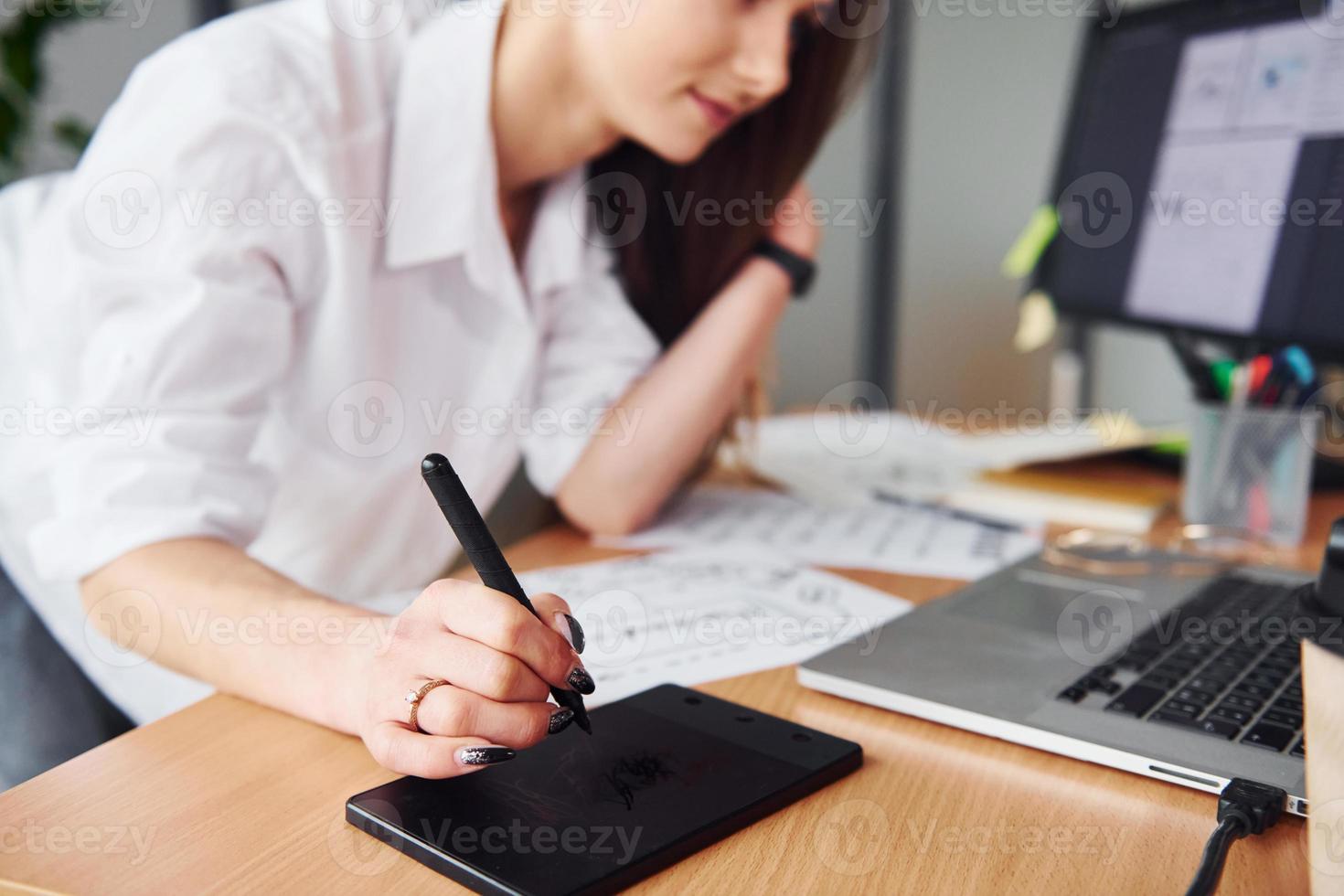 Active working. Young adult woman in formal clothes is indoors in the office photo