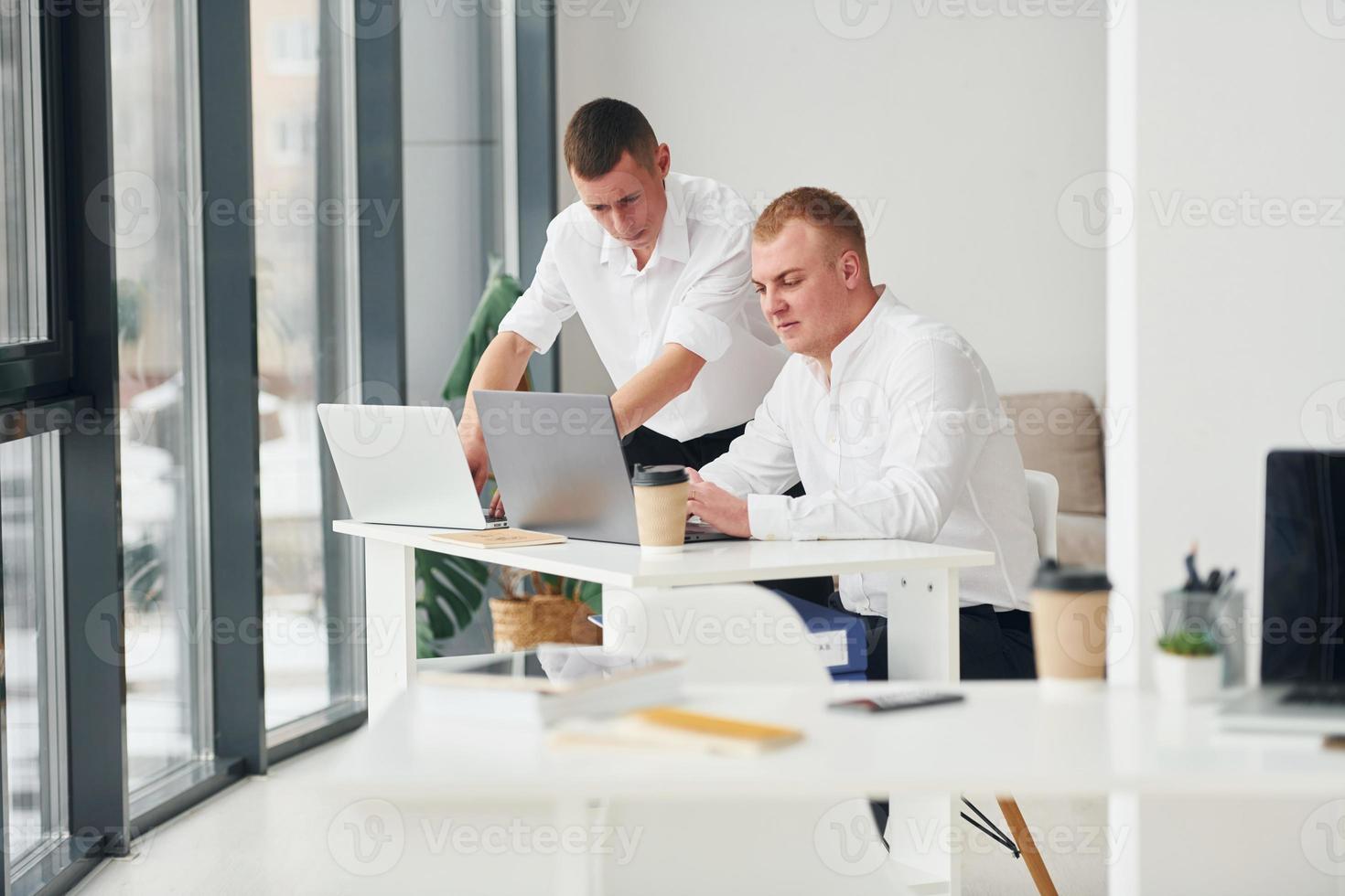 Two male office workers in formal clothes working together photo