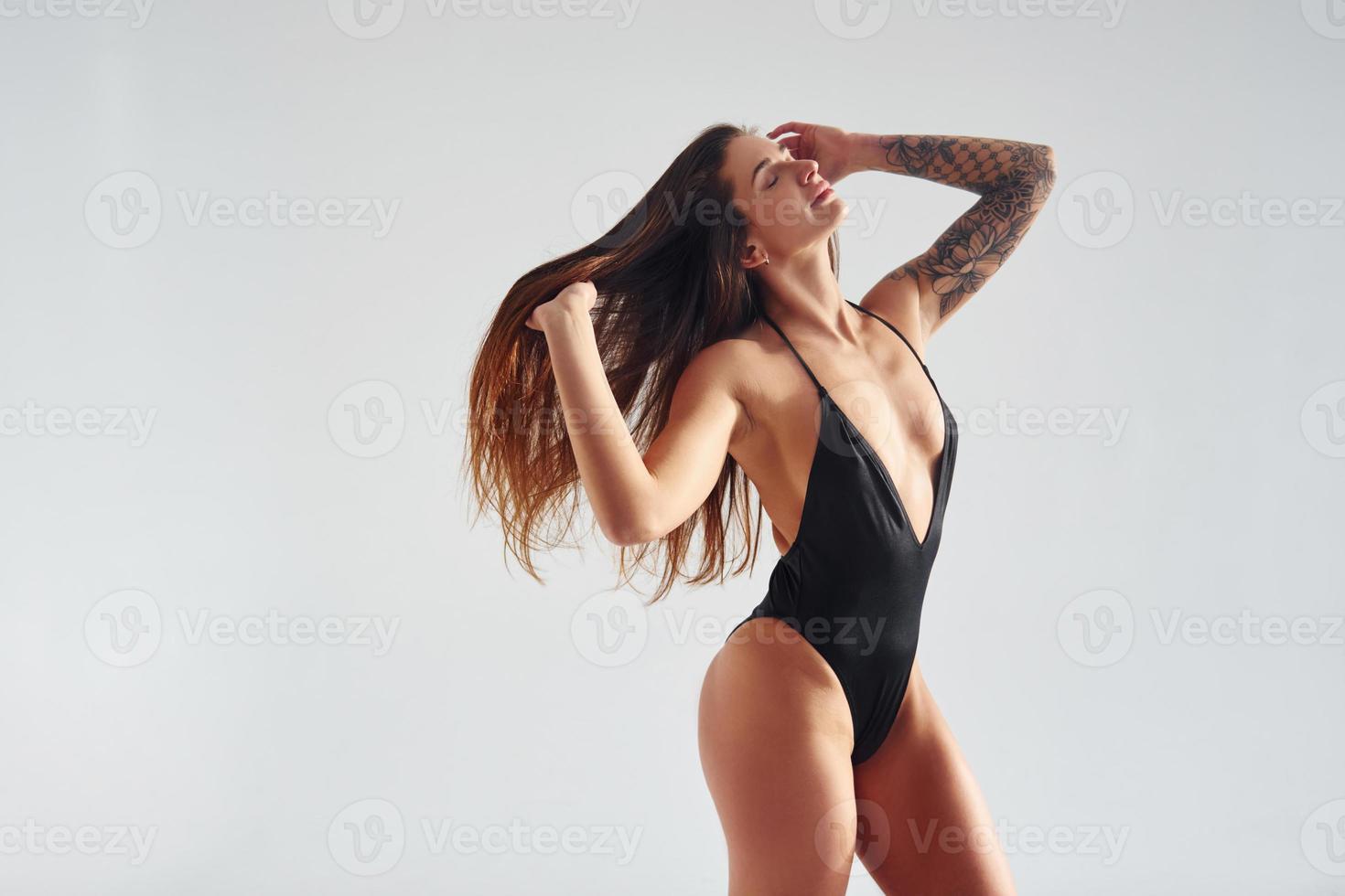 Standing and posing. Beautiful seductive sporty woman with sexy body is in the studio photo