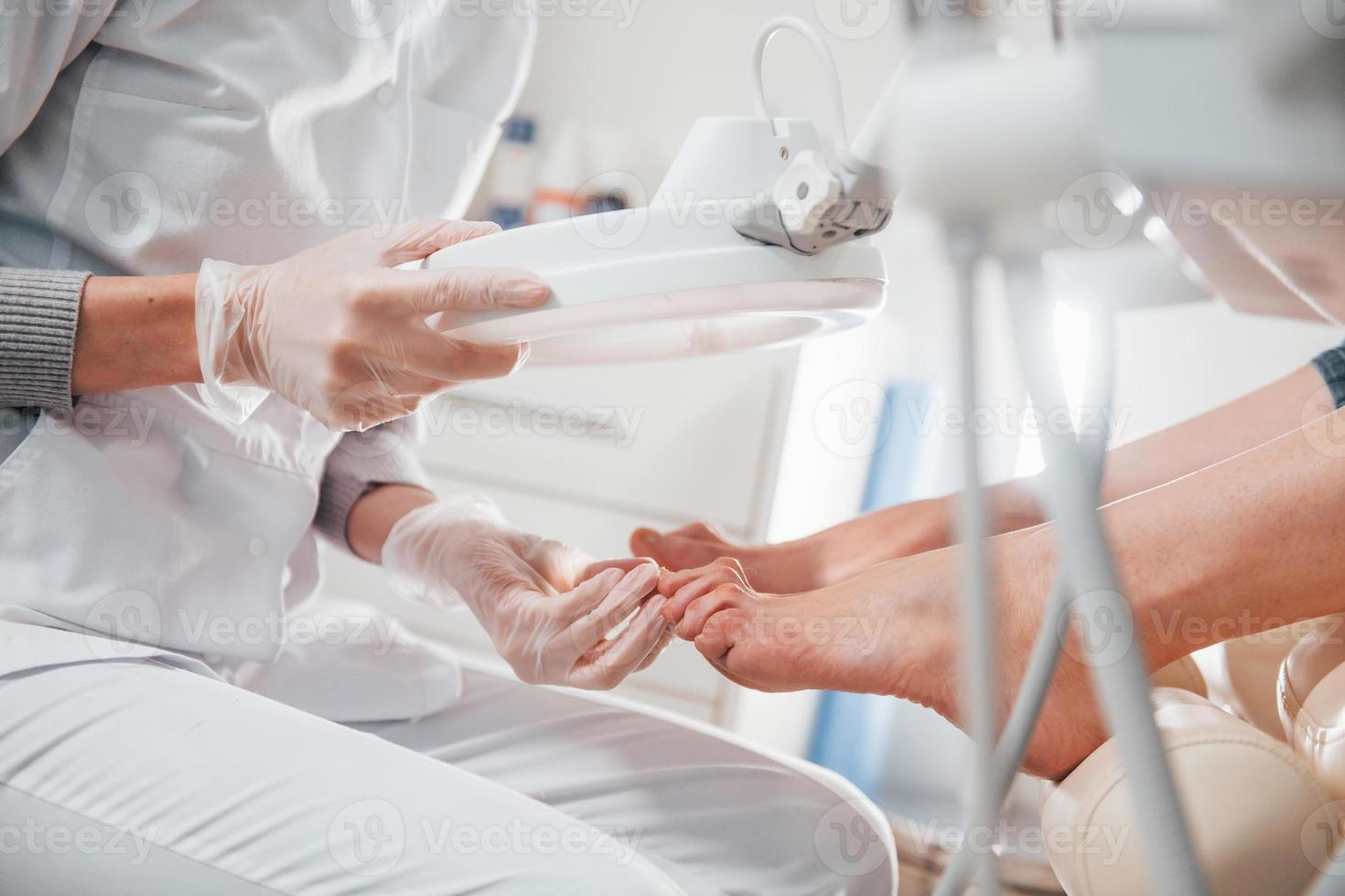 Woman lying down and have operation on her feet by professional clinic worker photo