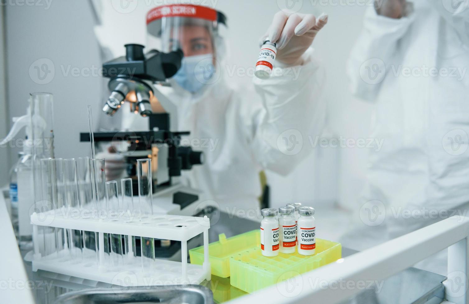 Female medical workers in protective uniform works on COVID-19 vaccine photo