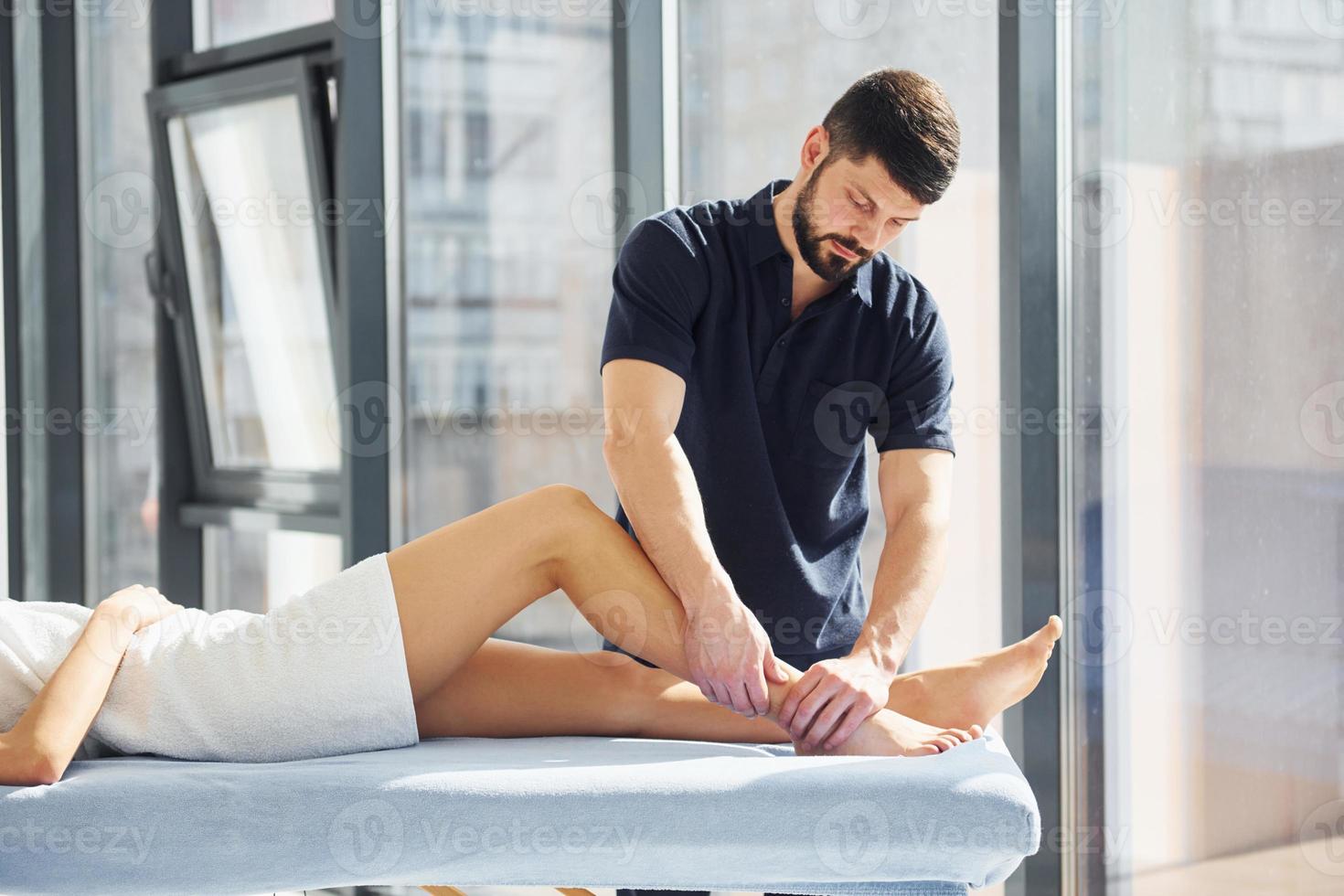 Guy does legs massage. Young woman is lying down when man serves her at spa photo