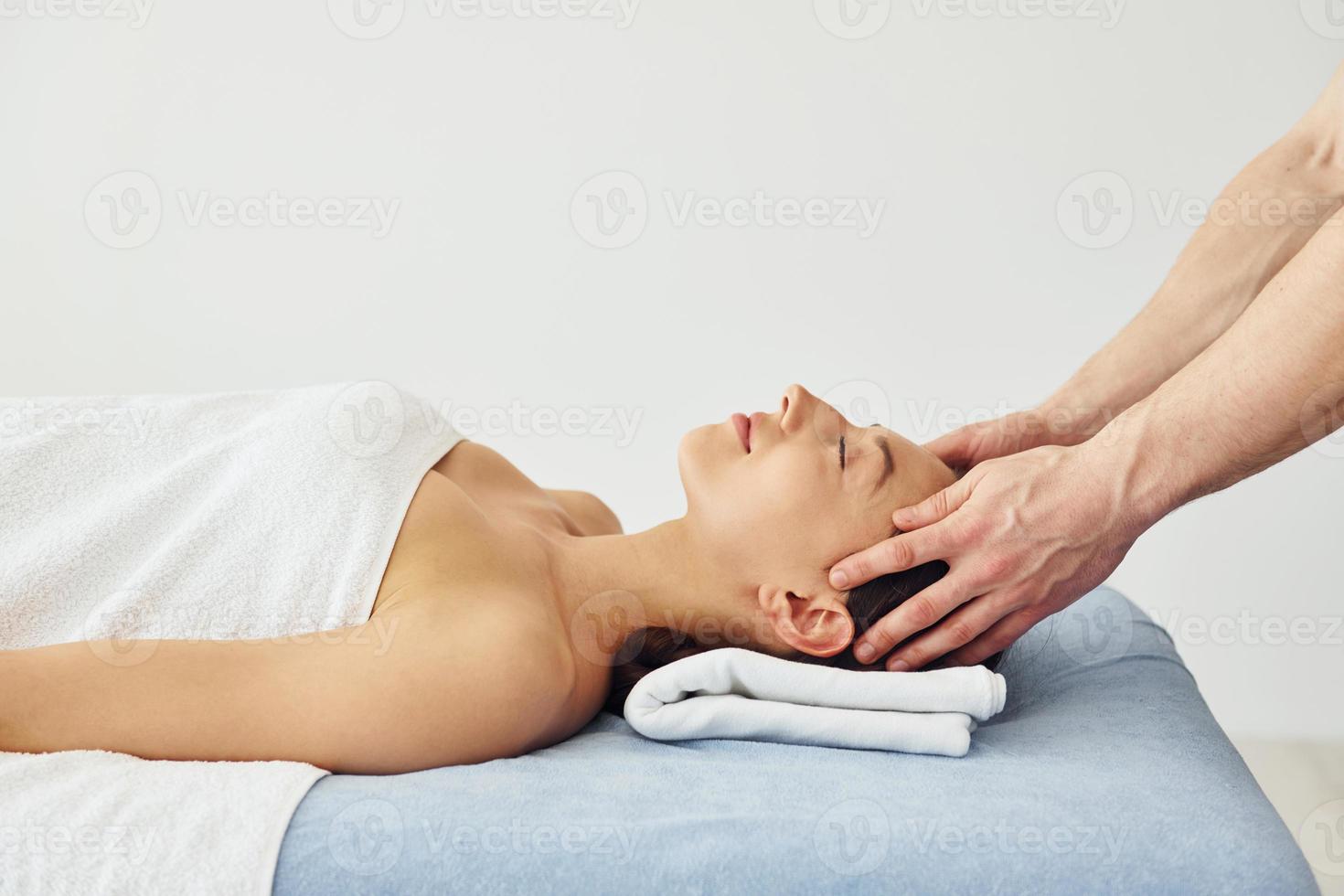masaje de cabeza. la mujer joven está acostada cuando el hombre le hace el procedimiento en el spa foto
