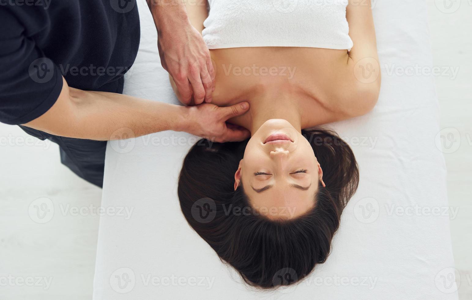 la mujer joven está acostada cuando el hombre hace un masaje de su cuerpo en el spa foto