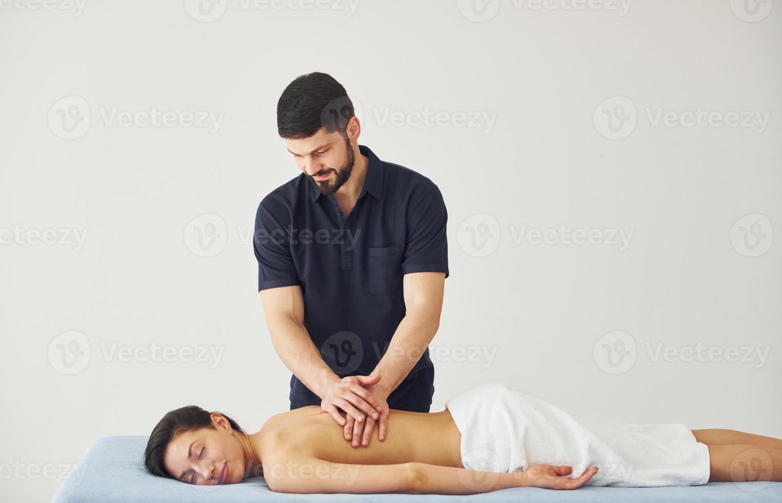 Young woman is lying down when man doing massage of her back at spa photo