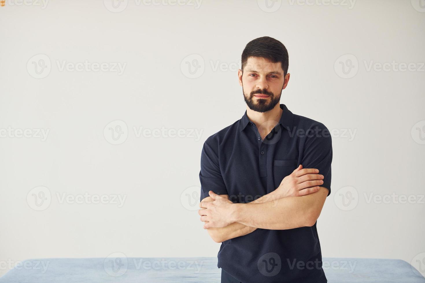 Serious man in shirt standing indoors against white background photo