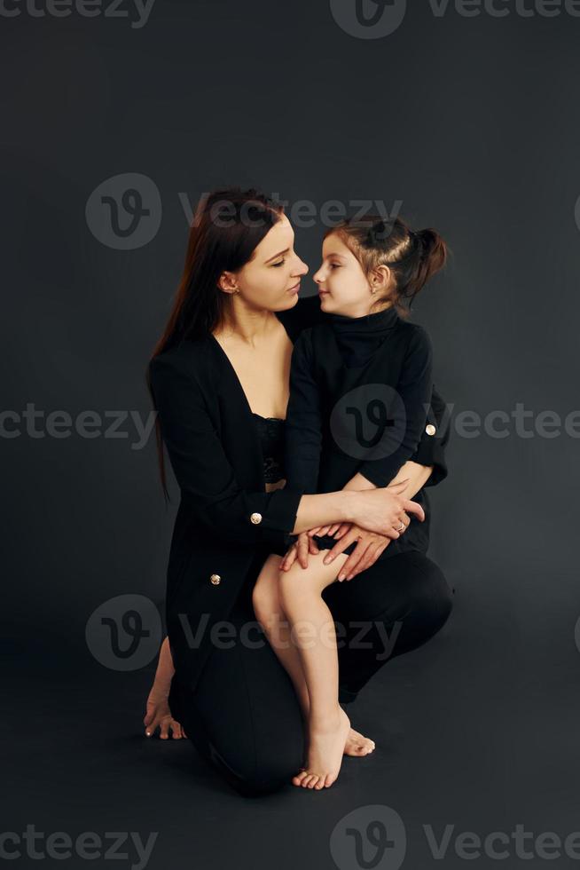 Mother and daughter is together in the studio against black background photo