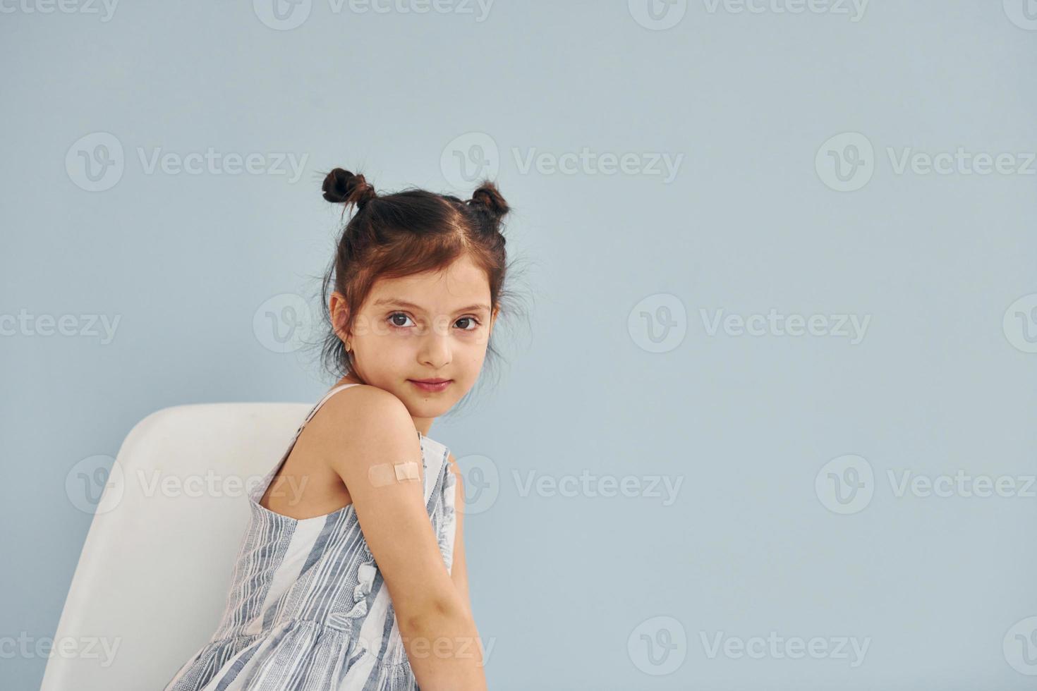 Cute little girl sits after vaccine injection indoors in hospital photo