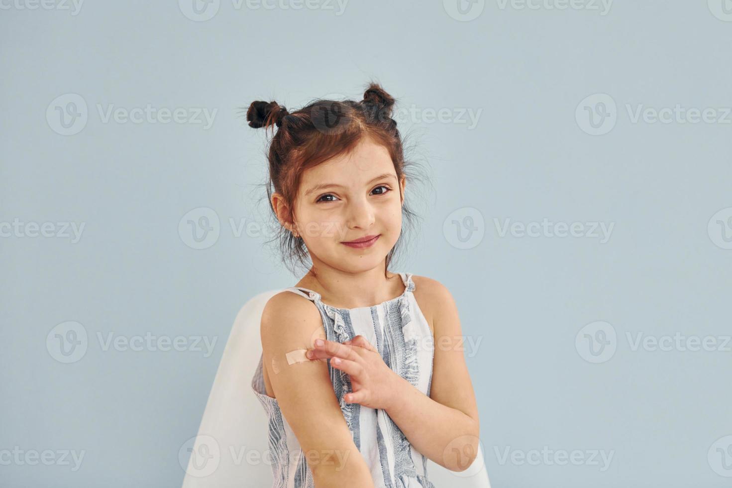 Cute little girl sits after vaccine injection indoors in hospital photo