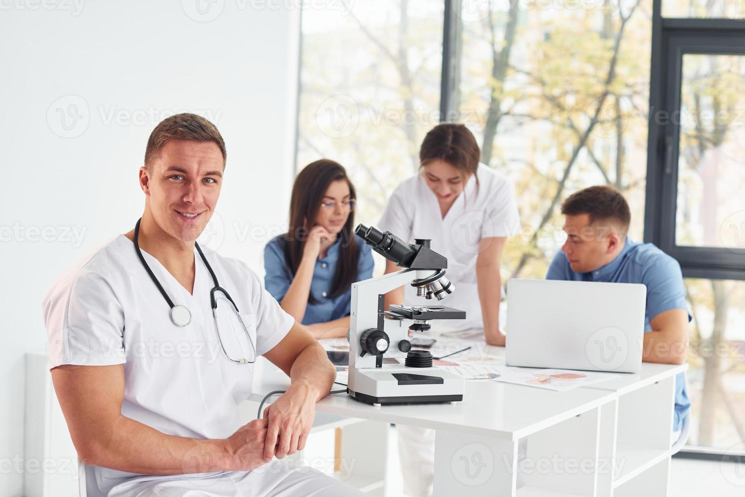 utilizando microscopio. grupo de médicos jóvenes está trabajando juntos en la oficina moderna foto