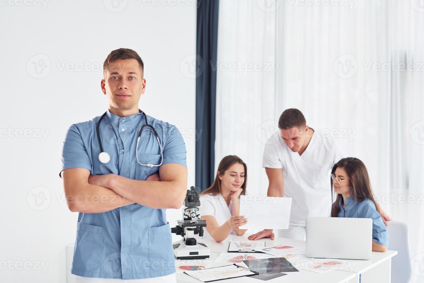 hombre de pie y posando. grupo de médicos jóvenes está trabajando juntos en la oficina moderna foto