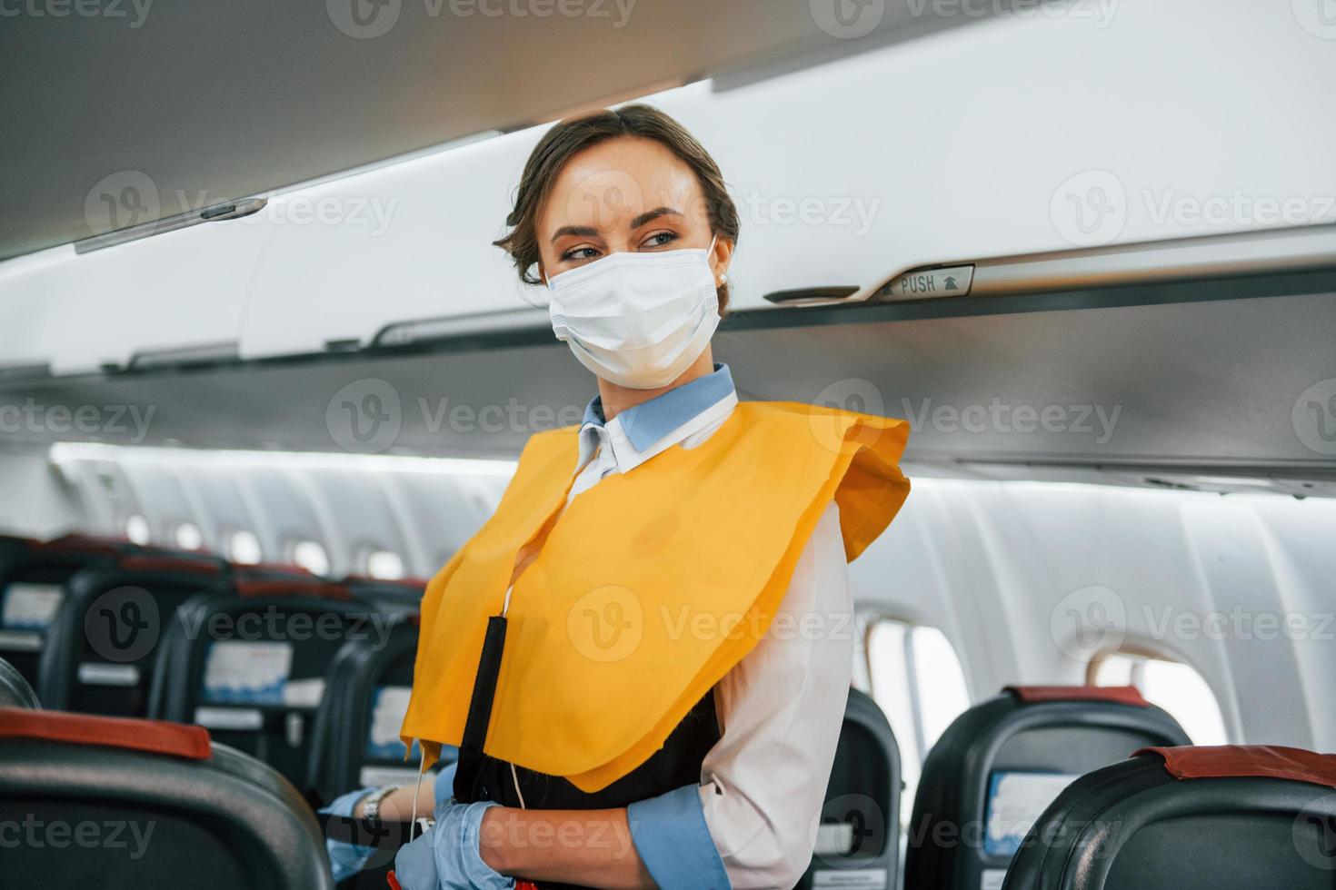 Safety instructions. Young stewardess on the work in the passanger airplane photo