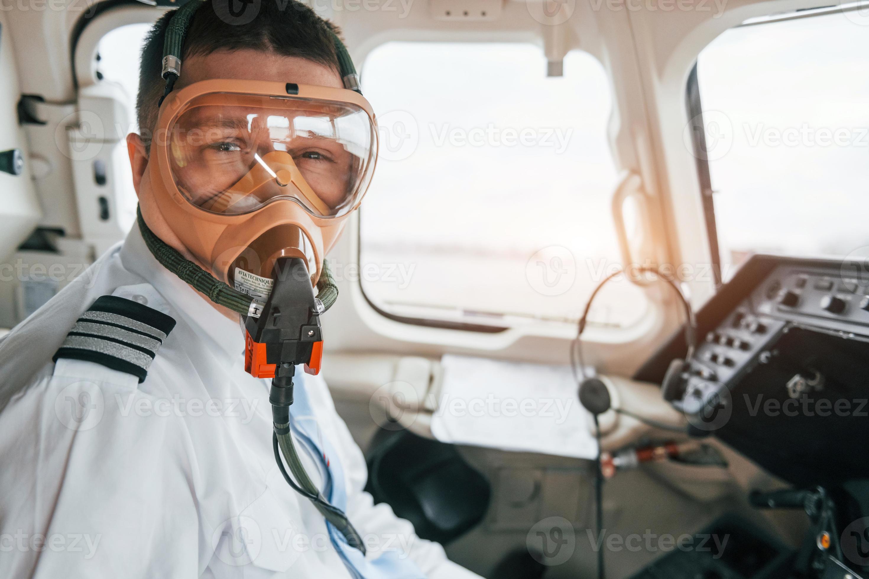 In oxygen mask. Pilot on the work in the passenger airplane. Preparing