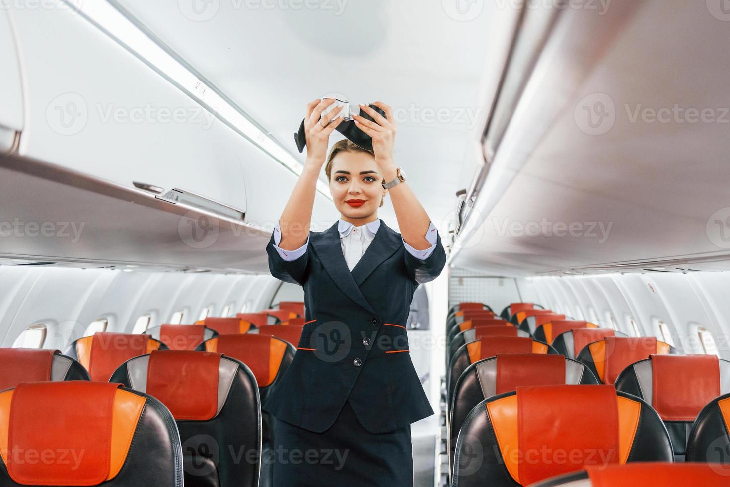 instrucciones de seguridad. joven azafata en el trabajo en el avión de pasajeros foto