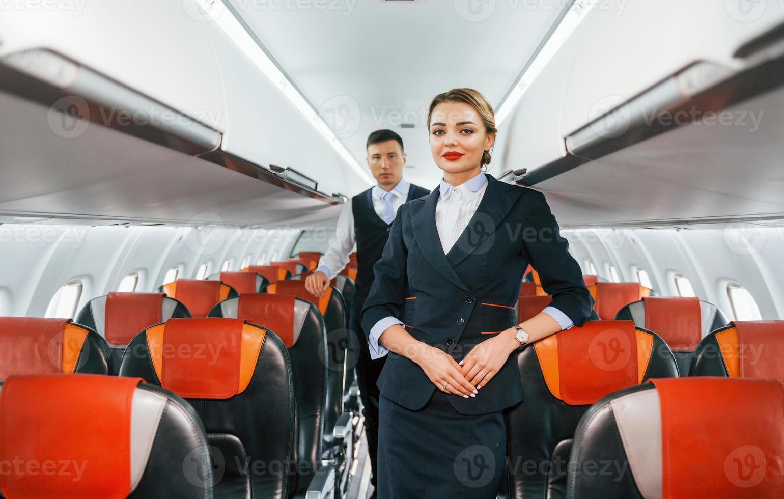 Young stewardess with steward on the work in the passanger airplane photo