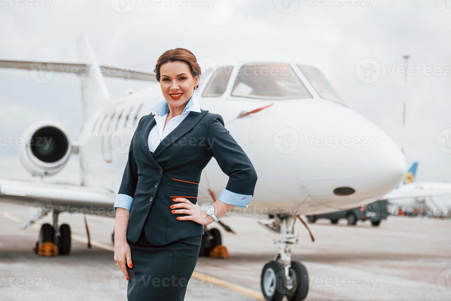 joven azafata posando para la cámara al aire libre cerca del avión foto