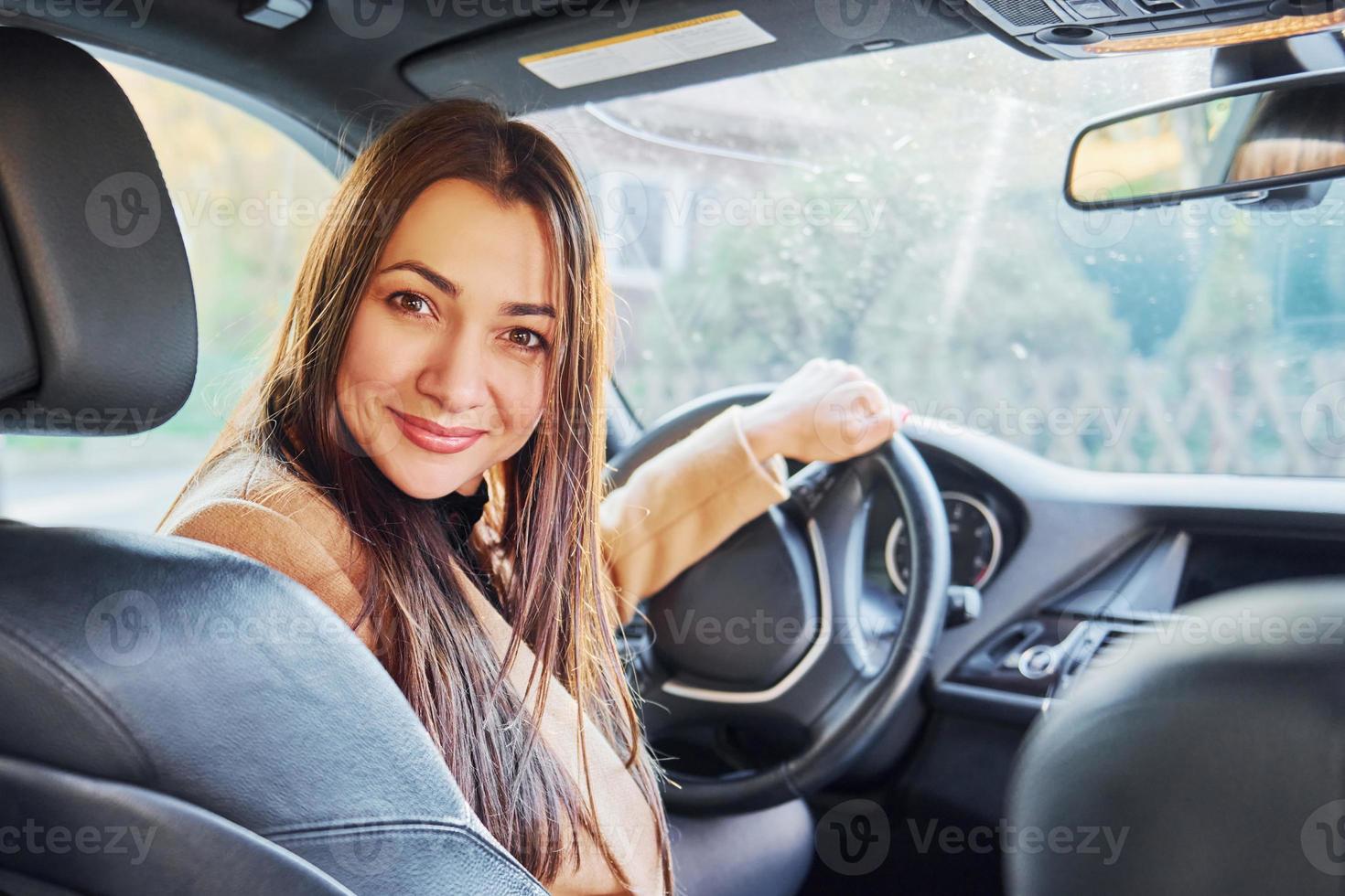 Vehicle interior. Woman is sitting in modern black colored automobile photo