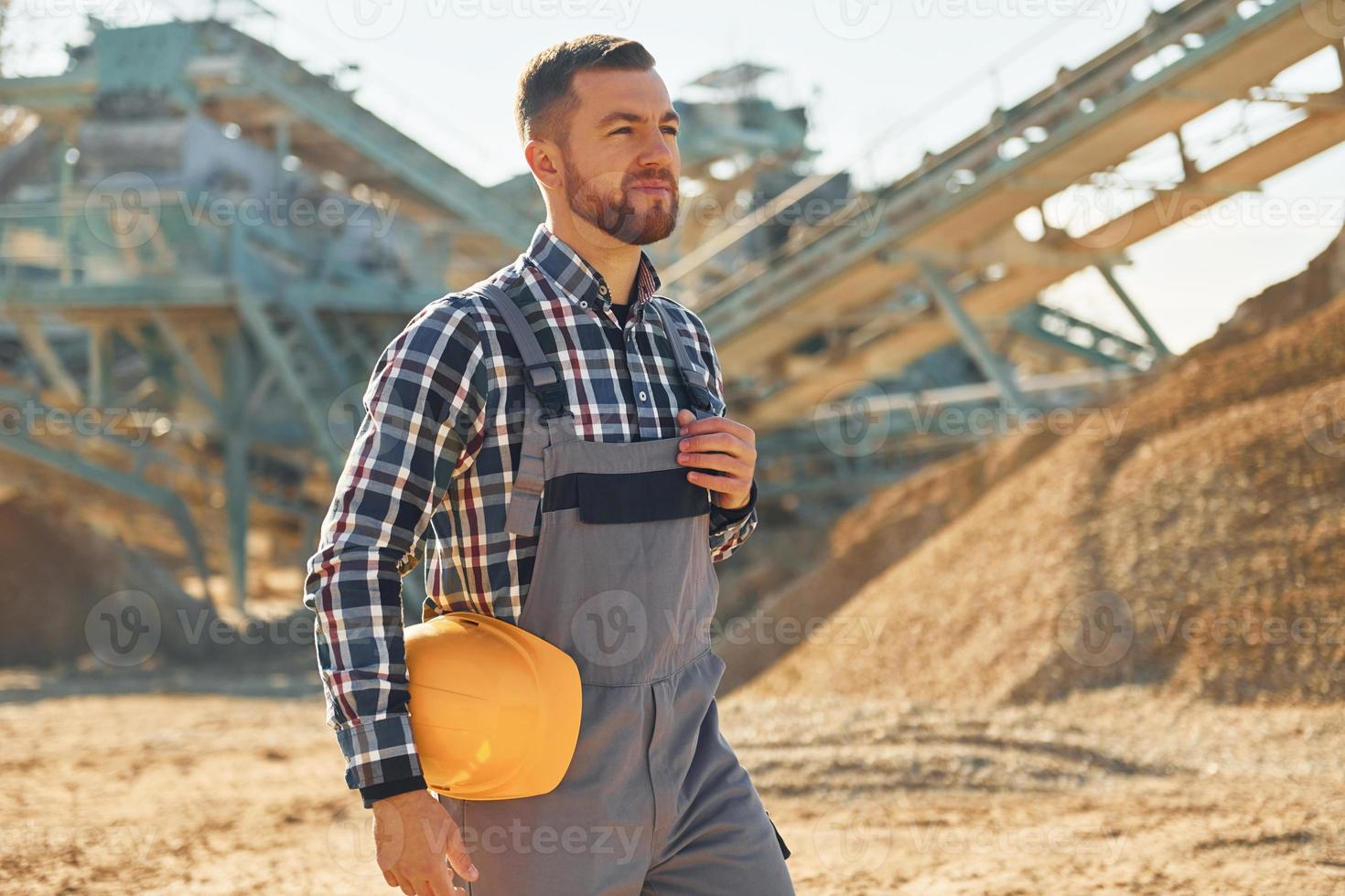 Casually walking. Construction worker in uniform is on the quarry photo