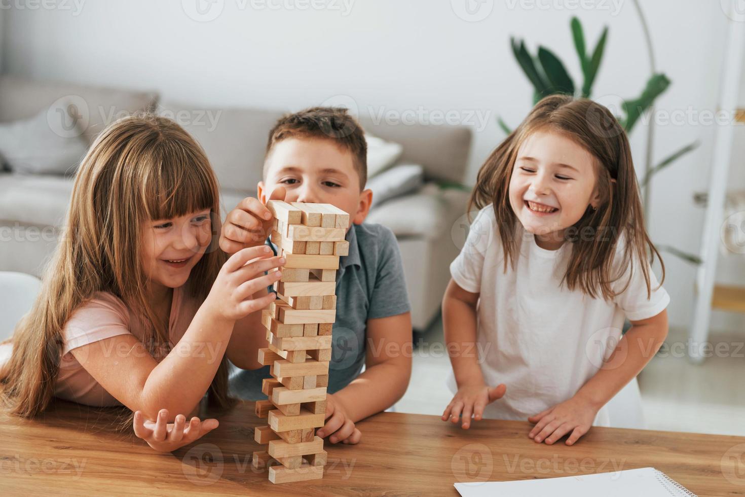 Jumbling tower game. Kids having fun in the domestic room at daytime together photo