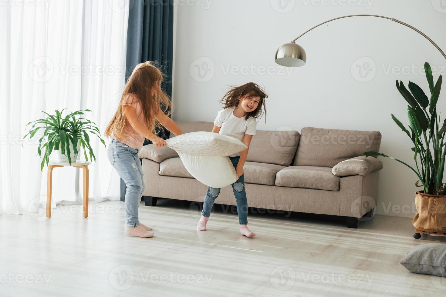 Running with pillows. Kids having fun in the domestic room at daytime together photo