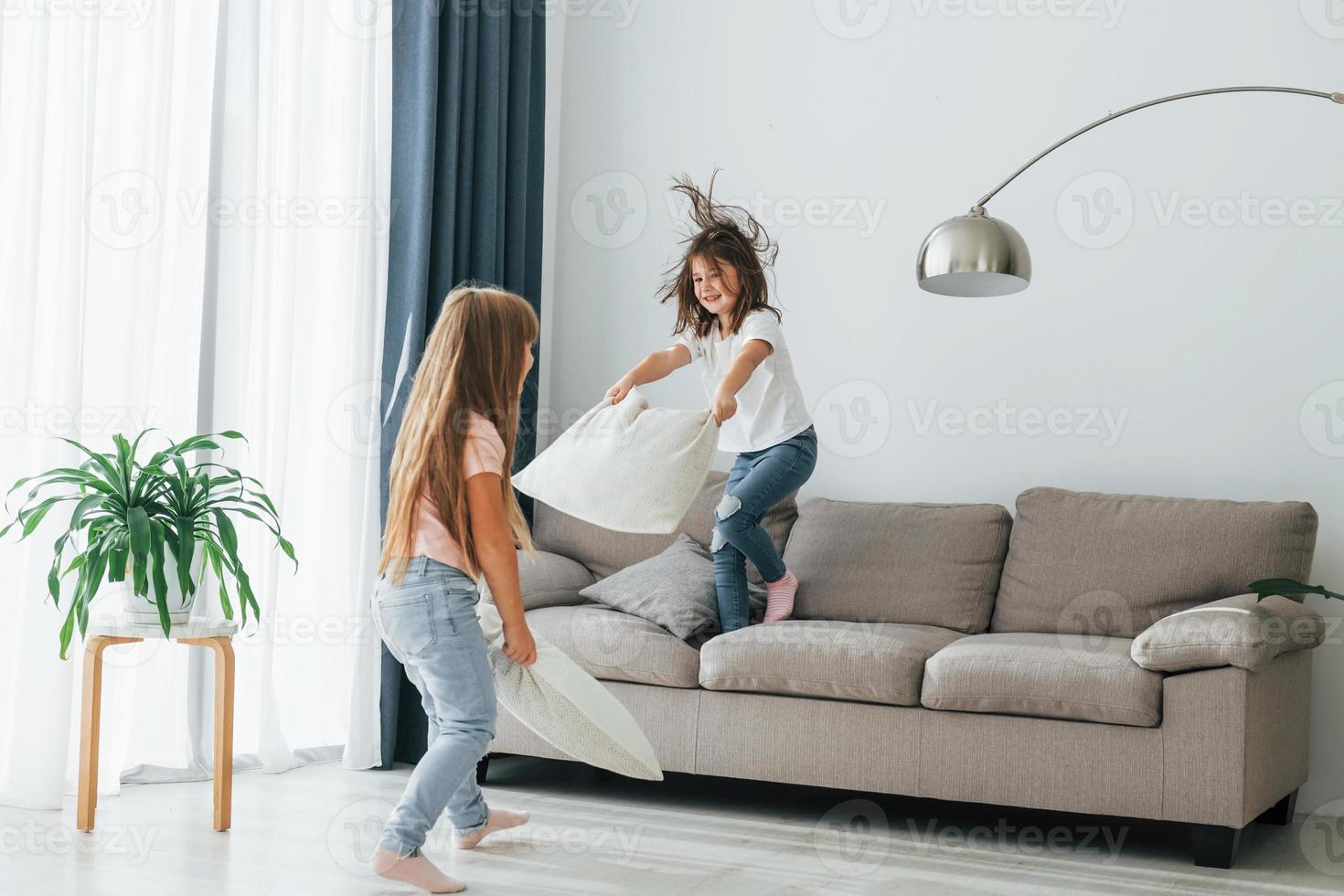 Running with pillows. Kids having fun in the domestic room at daytime together photo