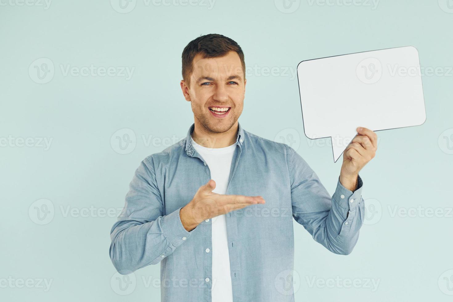 Smiling and having good mood. Man standing in the studio with empty signs for the text photo